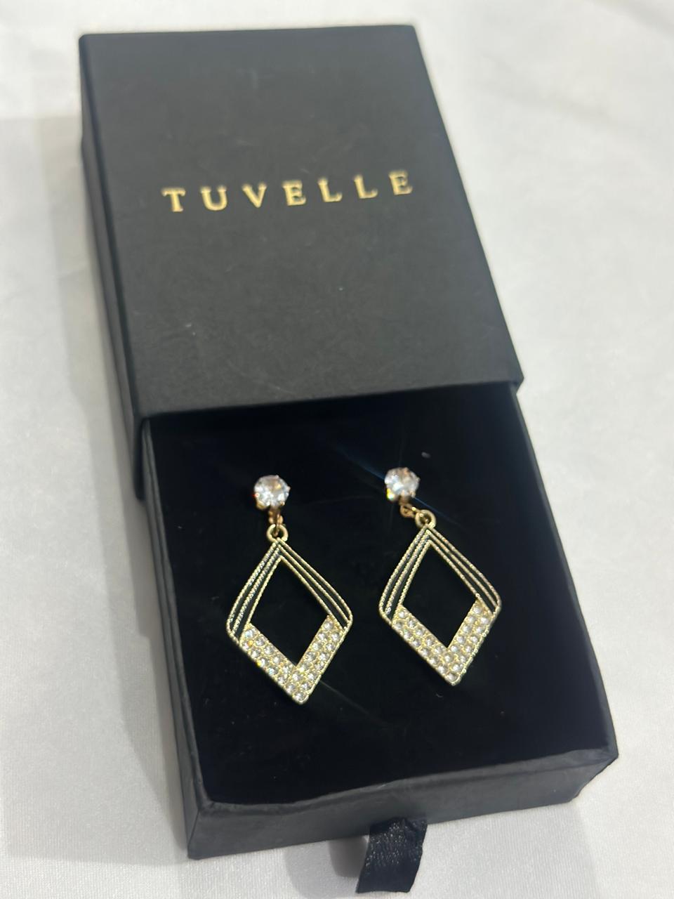Aria geometric sparkle earrings beside a TUVELLE box on a marble background