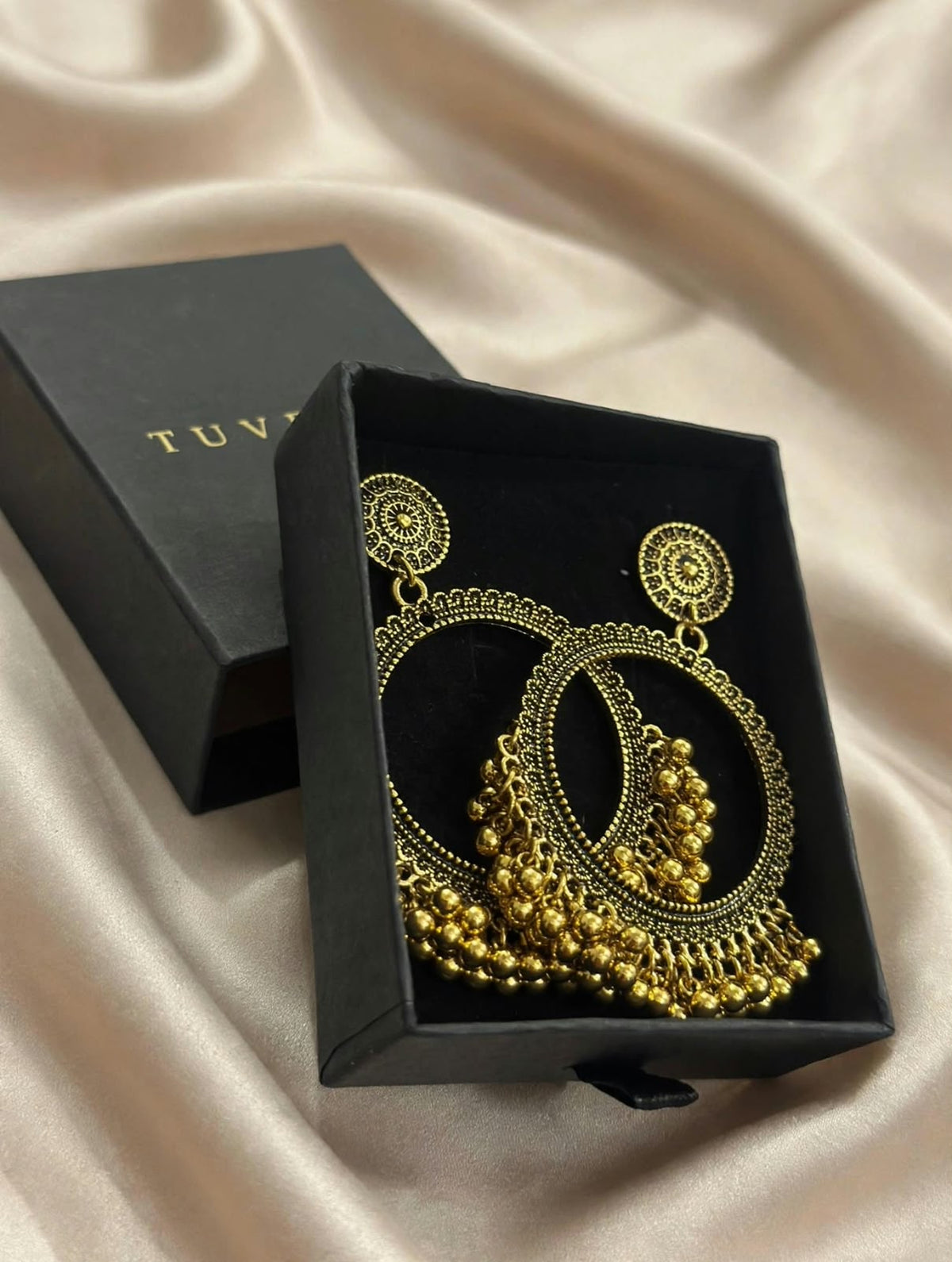 Close-up of ornate gold-tone chandbali earrings and dangling beads