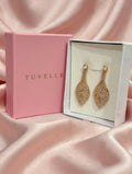 Close-up of gold-tone sparkling leaf drop earrings in a white jewellery box