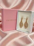 Close-up of gold-tone sparkling leaf drop earrings in a white jewellery box