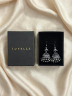 Close-up of antique silver-tone jhumka earrings with patterned domes and dangling bead fringe