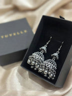 Top view of silver-tone jhumka earrings in black TUVELLE packaging on cream satin