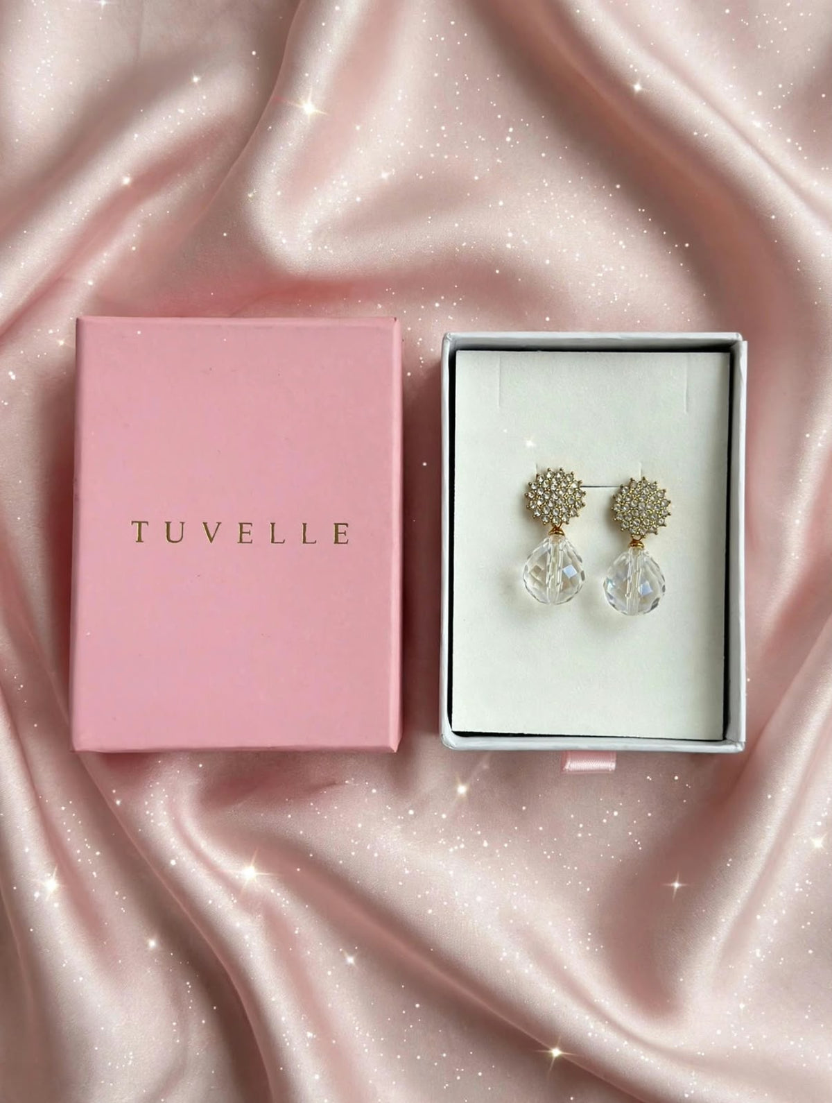 Close-up of sparkling floral-inspired earrings with clear faceted teardrop pendants