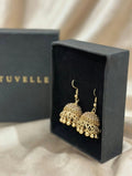 Antique gold-tone jhumka earrings with dangling beads beside a black TUVELLE box