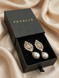 Close-up of sparkling floral-inspired earrings with white pearl-look drops and gold-tone accents
