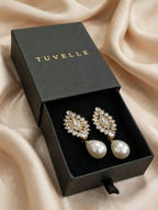 Close-up of sparkling floral-inspired earrings with white pearl-look drops and gold-tone accents