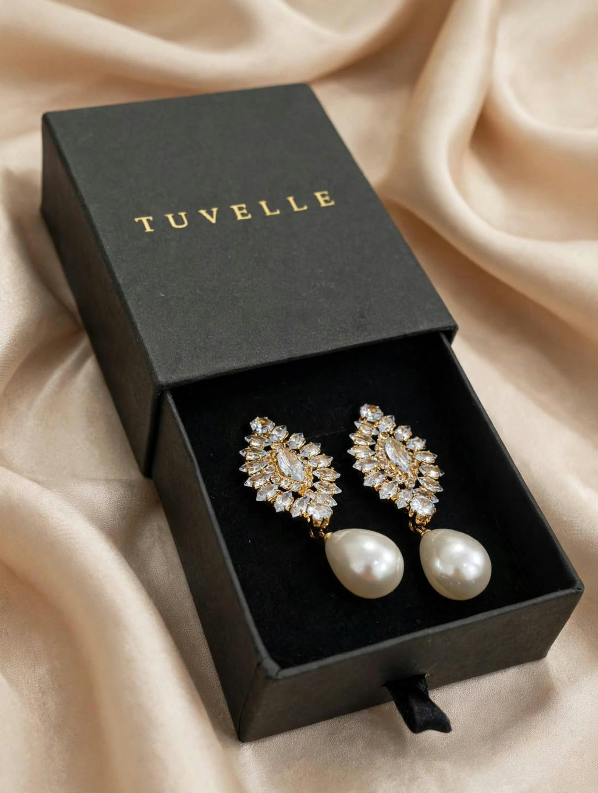 Close-up of sparkling floral-inspired earrings with white pearl-look drops and gold-tone accents