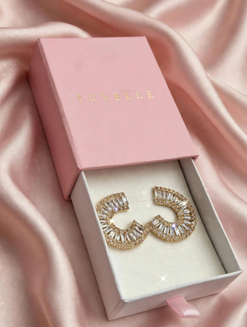Close-up of gold-tone C-shaped earrings with fan-arranged clear sparkling accents