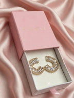 Close-up of gold-tone C-shaped earrings with fan-arranged clear sparkling accents