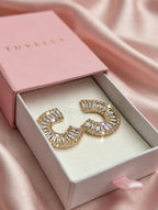 Gold-tone sparkling C-hoop earrings in a pink TUVELLE box on pink satin